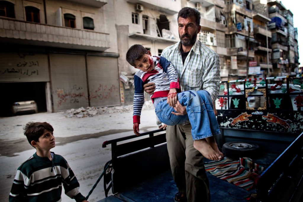 Sexårige Mustafa bärs in på sjukhuset av sin far. Mustafa var ute och lekte med sin kusin när han träffades av splitter från en granat. Foto: NICLAS HAMMARSTRÖM