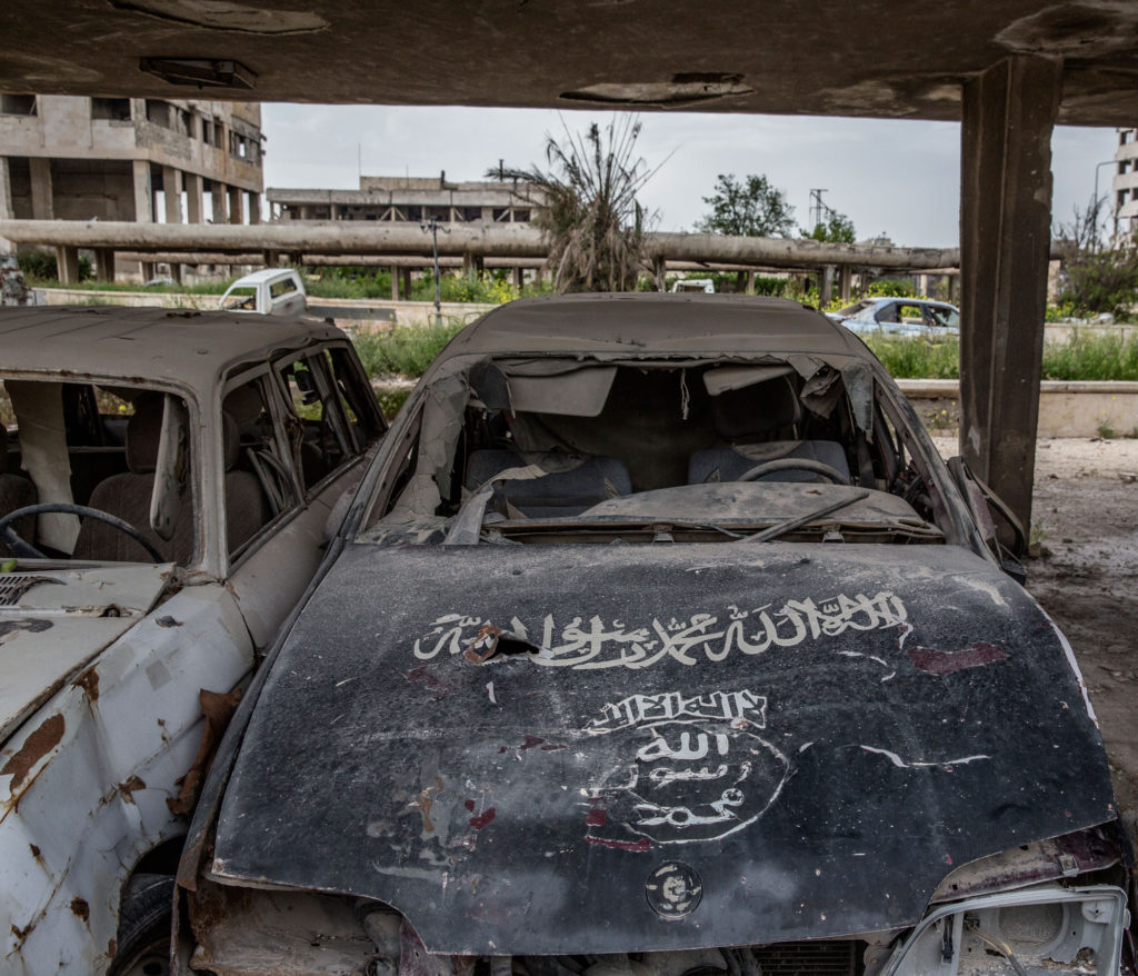 Utbrända bilar med skrifter som används av både Nusrafronten och Islamiska staten. Foto: MAGNUS WENNMAN